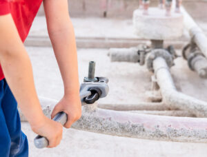 Children using a heavy-duty straight pipe plumbing wrench to repair a pipe.